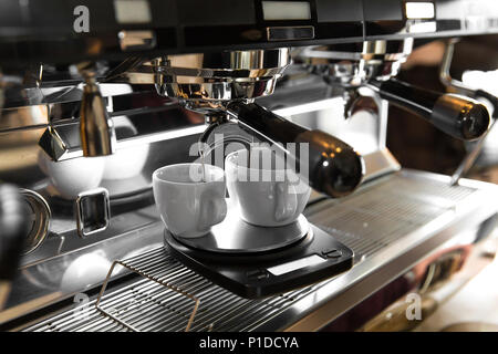 Caffè espresso italiano macchina su un contatore in un ristorante di erogazione di caffè appena fatto in due piccole coppe Foto Stock