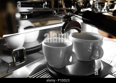 Caffè espresso italiano macchina su un contatore in un ristorante di erogazione di caffè appena fatto in due piccole coppe Foto Stock