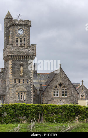 Fort Augustus, Scozia - Giugno 11, 2012: Closeup dell'Abbazia Highland Club torre dell orologio fronteggiata da giardino sotto pesante cloudscape. Foto Stock