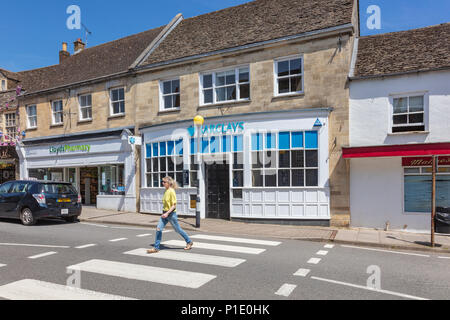 Sequenza 4 di 5, una donna attraversa le strisce pedonali in Malmesbury High Street al di fuori di Barclays Bank. Come ella velocità fino vi è il motion blur, Wiltshire, Regno Unito Foto Stock