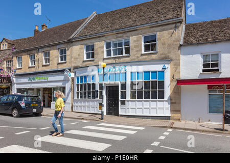 Sequenza 5 di 5, una donna attraversa le strisce pedonali in Malmesbury High Street al di fuori di Barclays Bank. Come ella velocità fino vi è il motion blur, Wiltshire, Regno Unito Foto Stock