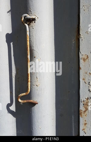 La porta di metallo gancio per la chiusura di una porta su un metallo sfondo striato, fotografia verticale. Foto Stock