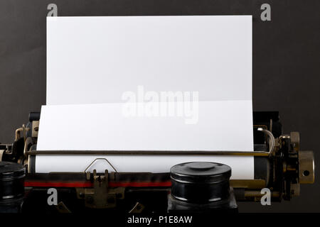 Close up della macchina da scrivere vintage con vuoto, foglio di carta bianco su sfondo nero Foto Stock