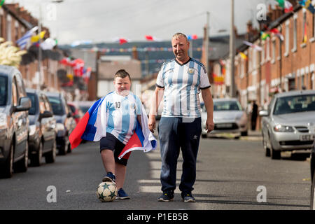 Iris nella parte occidentale di Belfast residente Turley sabbiosa e suo figlio Aaron Turley giocando a calcio per strada come lui e altri residenti hanno ottenuto in Coppa del Mondo febbre a creare un gioco a premi e raccogliere fondi per una festa di strada il giorno della finale della Coppa del mondo. Foto Stock