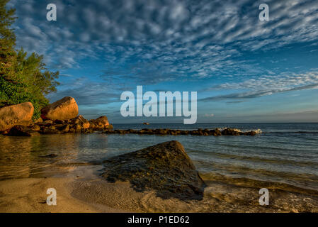 Una pittoresca spiaggia sul modo di Beau Vallon,Seychelles, su un golden ore di luce creando un suggestivo paesaggio con un cielo sgombro e Oceano Indiano del blu Foto Stock