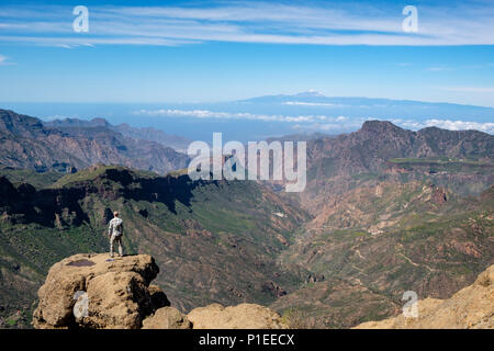 L'uomo guarda da Roque Nublo oltre il paese di montagna di Gran Canaria verso il vulcano Teide, Gran Canaria Isole Canarie Spagna Foto Stock