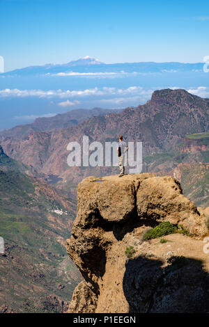 L'uomo guarda da Roque Nublo oltre il paese di montagna di Gran Canaria verso il vulcano Teide, Gran Canaria Isole Canarie Spagna Foto Stock