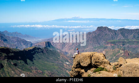 L'uomo guarda da Roque Nublo oltre il paese di montagna di Gran Canaria con il vulcano Teide All'orizzonte, Gran Canaria Isole Canarie Spagna Foto Stock