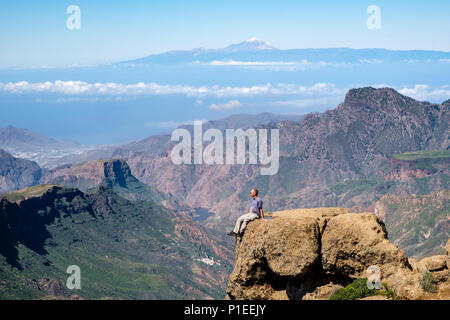 L'uomo guarda da Roque Nublo oltre il paese di montagna di Gran Canaria con il vulcano Teide All'orizzonte, Gran Canaria Isole Canarie Spagna Foto Stock