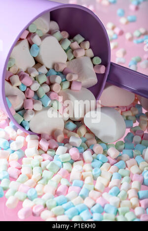 Violetta secchio con vari marshmallows su uno sfondo di colore rosa. Foto Stock