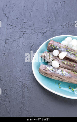 Filetti di aringhe con cipolle su una piastra di blu, una tradizionale delicatezza olandese. Delizioso pasto a base di pesce. Copia spazio. laici piatta Foto Stock