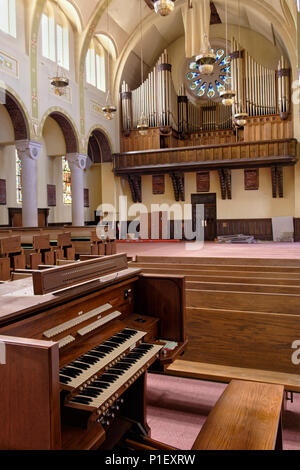 Chiesa abbandonata interno che mostra grande organo a canne con due tier tastiera e le panche in legno di quercia, ruvido e inutilizzate. Foto Stock