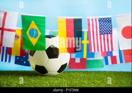 Mondo internazionale bandiera bunting appeso attorno a una seduta di calcio in erba Foto Stock