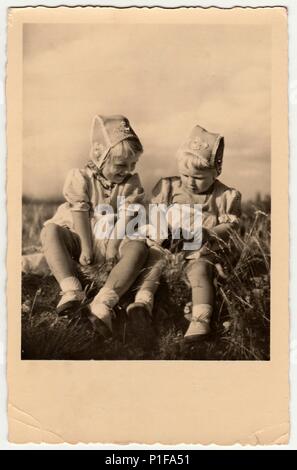 DRESDA, GERMANIA - CIRCA 1954: Foto d'epoca mostra le ragazze sit on grass. Indossano il cappello tradizionale per le ragazze. Vecchia foto in bianco e nero. 1950s. Foto Stock