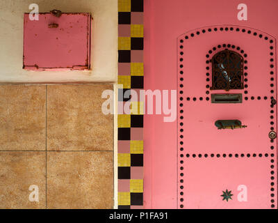 Urbano parete grunge sfondo rosa con la porta di metallo e piazza rosa sulla piastrella giallo. Foto Stock