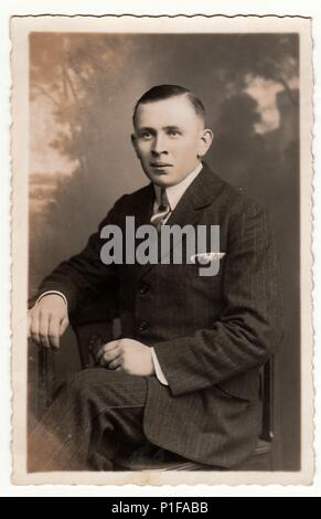 EILENBURG, GERMANIA - CIRCA 1920s: Foto d'epoca mostra le pose del giovane uomo in uno studio fotografico. Vecchia foto in bianco e nero. Antico ritratto studio. 1920s. Foto Stock