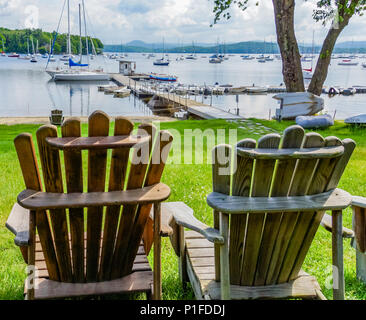 Due di legno sedie di Adirondack con una vista del lago con molte barche a vela ormeggiata Foto Stock