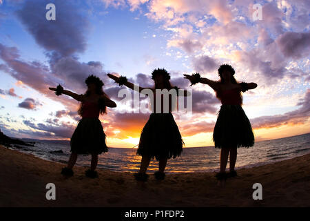 Tre danzatori di hula al tramonto a Palauea Beach, Maui, Hawaii. Foto Stock