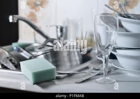 Un enorme pila di piatti non lavati nel lavello da cucina e sul bancone. Un sacco di utensili e apparecchi da cucina prima del lavaggio. Il concetto di dail Foto Stock