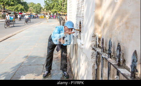 Uomo di bere acqua potabile pulita da una stazione di acqua nella città di Jaipur, India. Foto Stock