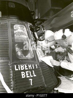 Astronauta Virgil I. Grissom salite in 'Liberty Bell 7' veicolo spaziale la mattina del 21 luglio 1961. Backup astronauta John Glenn assiste nell'operazione. Il Mercury-Redstone 4(MR-4) ha lanciato con successo la Liberty Bell 7 a 7:20 AM EST sulla luglio 21, 1961. Signor-4 era il secondo di una serie di successo degli Stati Uniti sottorbitale presidiato voli. Foto Stock