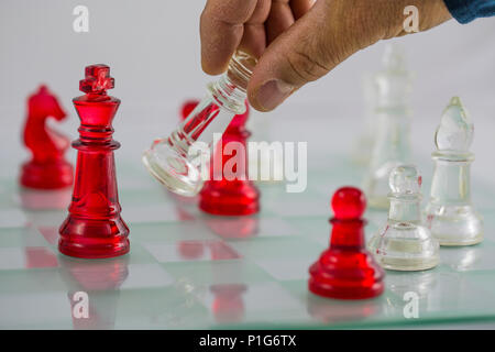 L'uomo il movimento dei pezzi su una scacchiera di vetro Foto Stock