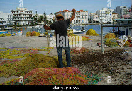 Pulizia del pescatore le sue reti al dock in Tinos, Cicladi, Grecia Foto Stock