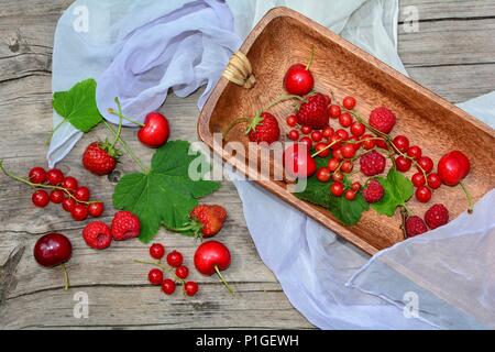 Ancora in vita con le uve secche di Corinto, fragole, ciliegie e lamponi su un tavolo rustico con panno di luce Foto Stock