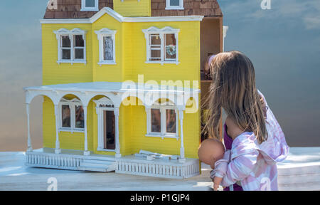 Una ragazzina è perso nella meraviglia come lei esamina questa splendida annata vecchia casa di bambola Foto Stock