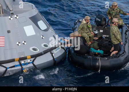 Stati Uniti Navy divers e altro personale in una barca Zodiac fissare un cablaggio attorno a una versione di prova di Orion modulo di equipaggio in corso durante la prova di recupero 5 nell'Oceano Pacifico al largo della costa della California su 28 Ottobre, 2016. Membri del New York Air National Guard la 106ª Ala di salvataggio parteciperà a una missione nelle Hawaii progettato per testare la capsula spaziale tecniche di recupero e attrezzature, sebbene essi non funzioneranno con un simulatore di capsula come questo.Orion è l'esplorazione spaziale progettato per trasportare gli astronauti a destinazioni non ancora esplorati dagli esseri umani. ( Foto cortesia della NASA) Foto Stock