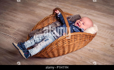 Poco bel bambino nel cestello, vestito in abiti eleganti Foto Stock