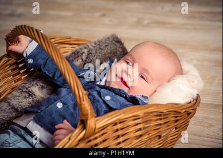 Poco bel bambino nel cestello, vestito in abiti eleganti Foto Stock