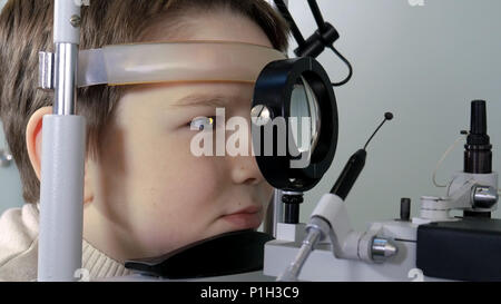 All'ottico optometrista eseguire visual prova sul campo del giovane ragazzo Foto Stock