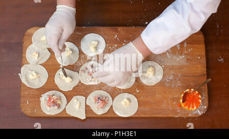 Mettere il pesce ripieno su un impasto, la preparazione di gnocchi fatti in casa Foto Stock
