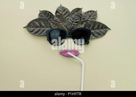 Il surrealismo sfondo per il testo, l'imitazione del concetto del viso. Occhiali da sole naturale di foglie e fiori di colore bianco su un verde grigio Sfondo. Flat Top laici Foto Stock