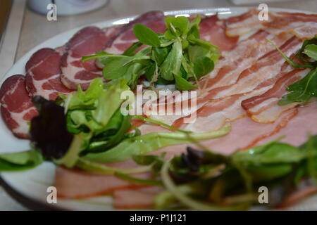 Delizioso cibo organico su un piatto di legno con olio d'oliva sul pane. Prosciutto, salame, peperoni, formaggio, salsiccia. Foto Stock