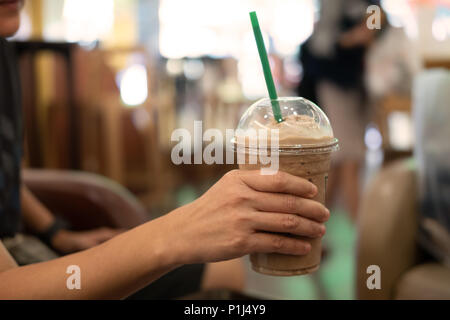 Donna che mantiene il vetro in plastica di caffè ghiacciato con latte, immagine per bevanda. Foto Stock