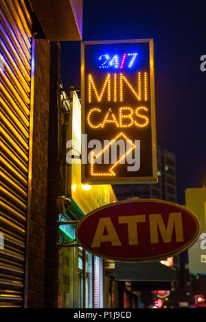 Un mini Cab e un cartello ATM, illuminato di notte su Old Street nel East End di Londra Foto Stock