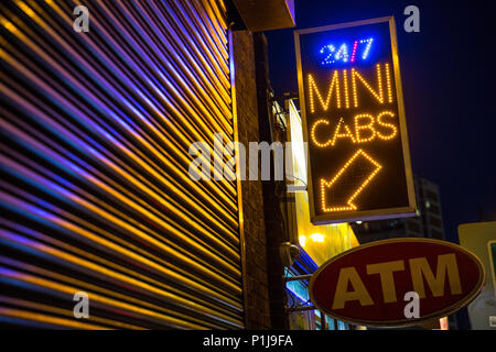 Un mini Cab e un cartello ATM, illuminato di notte su Old Street nel East End di Londra Foto Stock