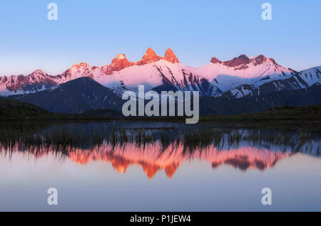 Picchi di montagna con alpenglow nelle Alpi francesi specchiata nel lago di montagna, Aiguille d'Arves, Hautes-Alpes, alpi, Francia Foto Stock