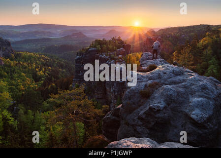 Fotografo sull'Heringsstein presso sunrise, Elba montagne di arenaria, Sassonia, Germania Foto Stock