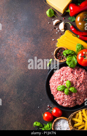 La carne macinata, la pasta e la verdura. Gli ingredienti per cucinare gli spaghetti alla bolognese. Vista dall'alto. Verticale. Foto Stock