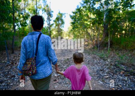 La madre cammina con sua figlia naturale nel pomeriggio la luce attraverso una foresta, Paluma Range National Park, Rollingstone QLD, Australia Foto Stock