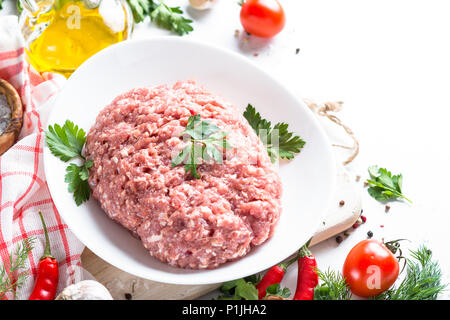 Carni macinate con ingredienti per la cottura sul tavolo bianco. Foto Stock