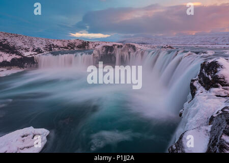 Luce della Sera su cascate Godafoss a ghiaccio e neve in inverno, altopiani, Islanda Foto Stock