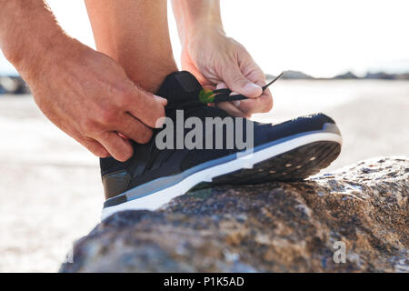 Close up di un uomo di legatura passalacci di legatura sul suo sneakers all'aperto Foto Stock