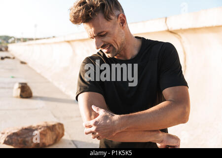 Ritratto di un ferito uno sportivo che soffre di un gomito dolore stando all'aperto Foto Stock