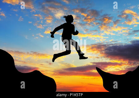 Donna salto oltre i canyon presso un tramonto Foto Stock