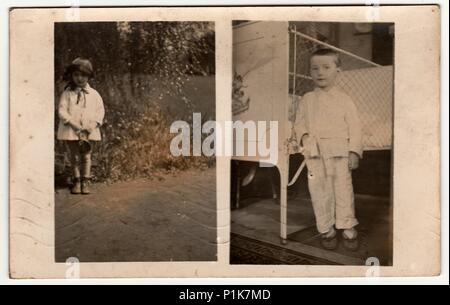 MALENICE (VOLARY), LA REPUBBLICA CECOSLOVACCA - 15 LUGLIO 1931: Foto d'epoca mostra che il ragazzo indossa pigiami, si trova accanto ad un letto di ferro e una bambina si pone all'aperto. Fotografia d'antiquariato in bianco e nero. 1930s Foto Stock