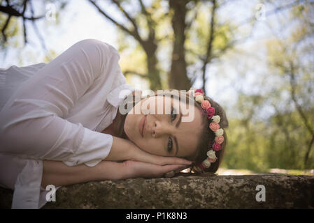 Donna sorridente indossando un Fiore di Acconciatura di giacente su una parete Foto Stock